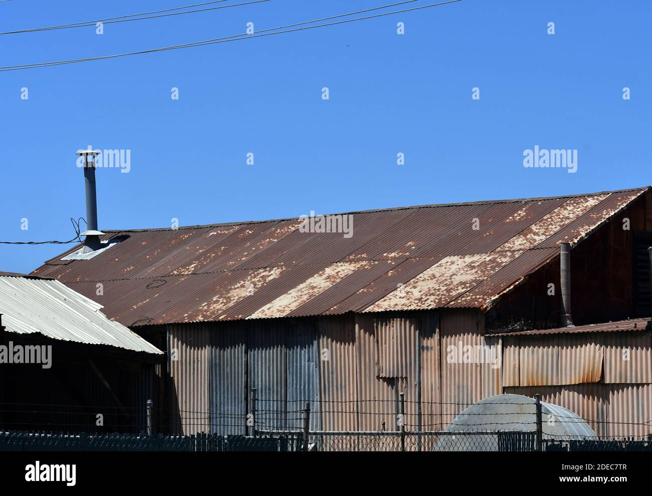 Eine Nahaufnahme einer rostigen alten Metallhütte mit Elektrische Verdrahtung unter blauem Himmel Stockfoto