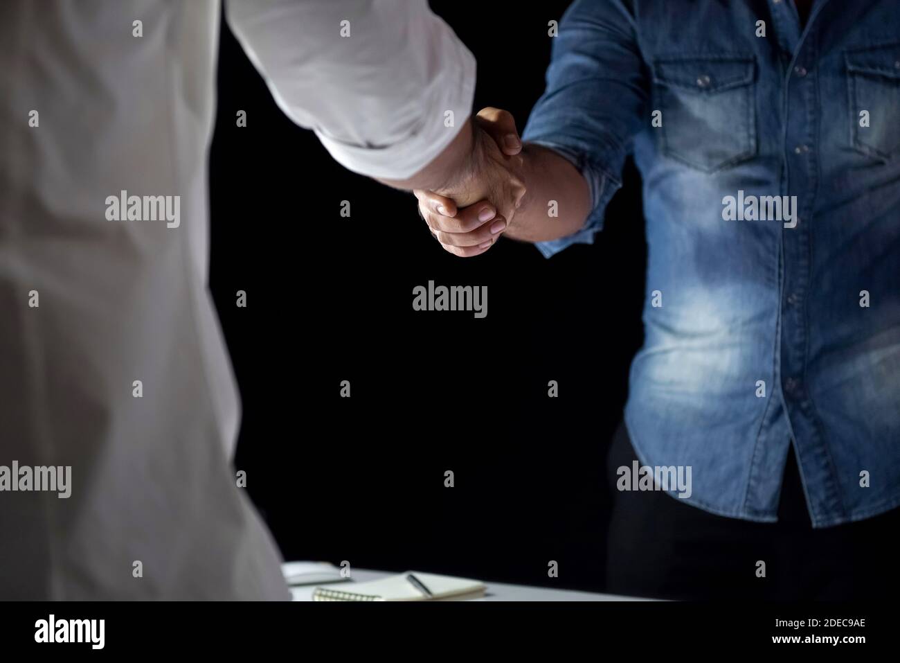Legere Geschäftsleute machen Handshake während der Sitzung in der Nacht Dunkler Schattenhintergrund Stockfoto