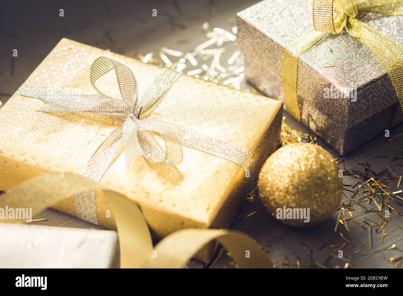 Splitter und Gold schimmernde Weihnachts-Geschenkschachteln mit glitzernder Dekoration Artikel auf Holztisch für die festliche Jahreszeit Stockfoto