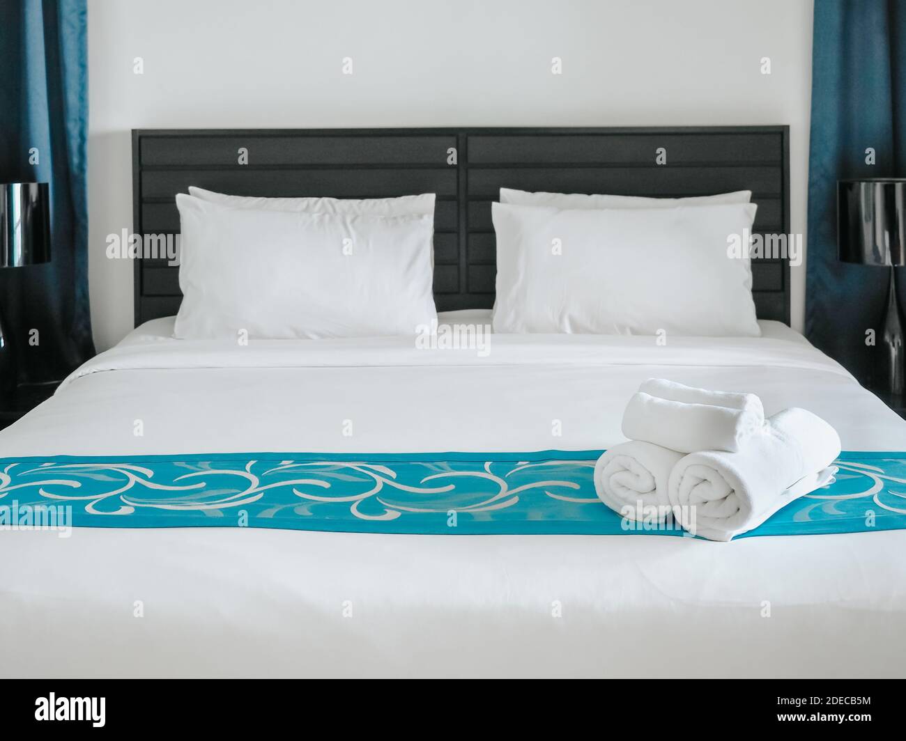 Weiße Handtücher auf der Bettdekoration im Schlafzimmer mit Kissen. Handtücher und weiße Bettwäsche im modernen Hotel. Stockfoto