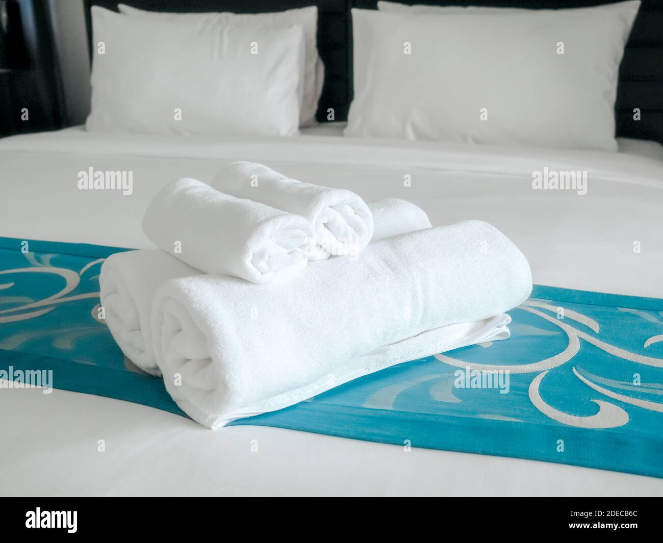 Weiße Handtücher auf der Bettdekoration im Schlafzimmer mit Kissen. Handtücher und weiße Bettwäsche im modernen Hotel. Stockfoto
