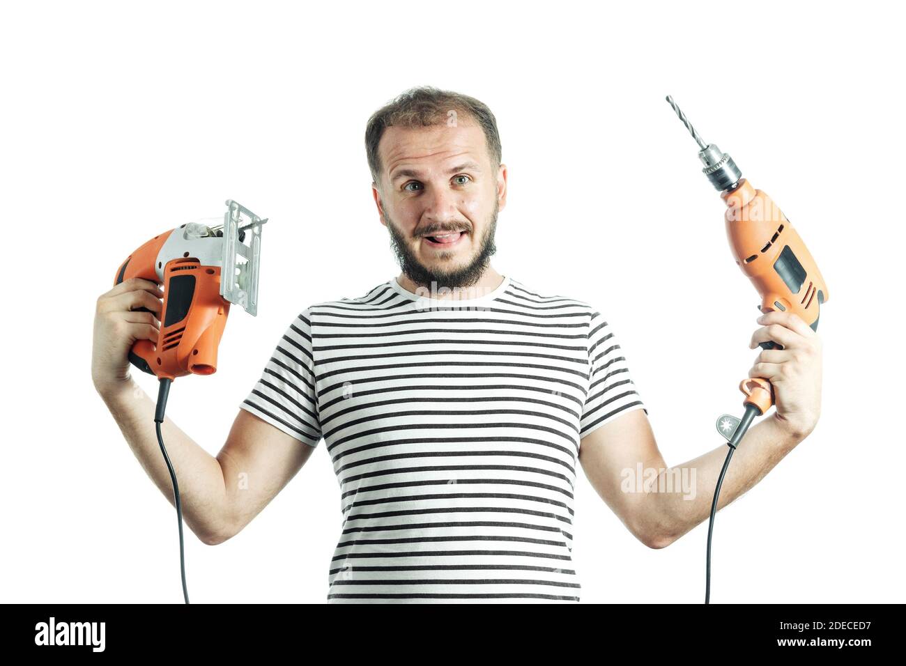 Ein dummer Mann hält einen Bohrer und ein elektrisches Puzzle in den Händen. So wählen Sie ein Elektrowerkzeug aus Stockfoto