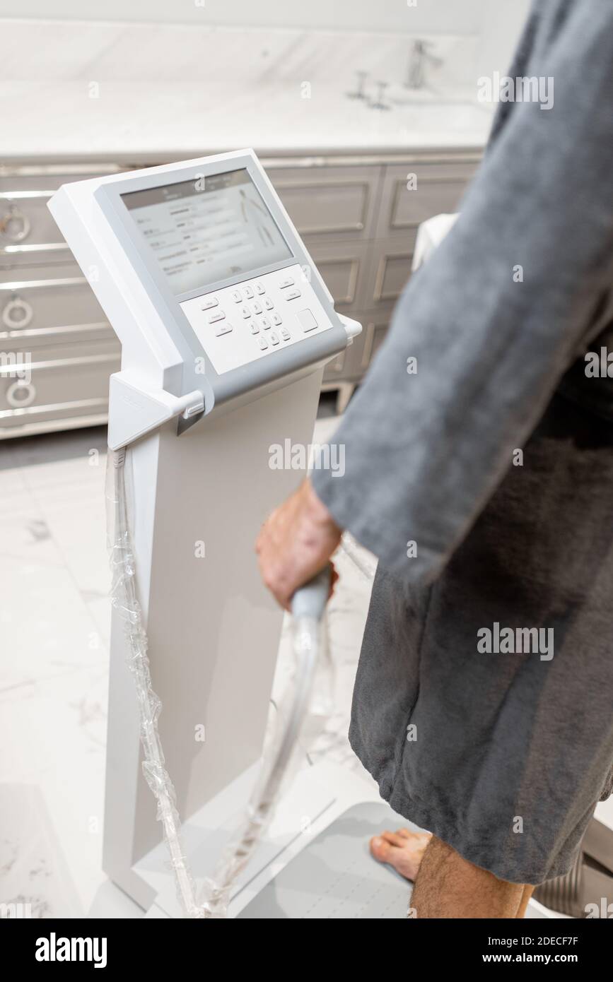 Mann misst Körperzusammensetzung Gleichgewicht, hält Griffe einer medizinischen Waage während InBody-Test Stockfoto