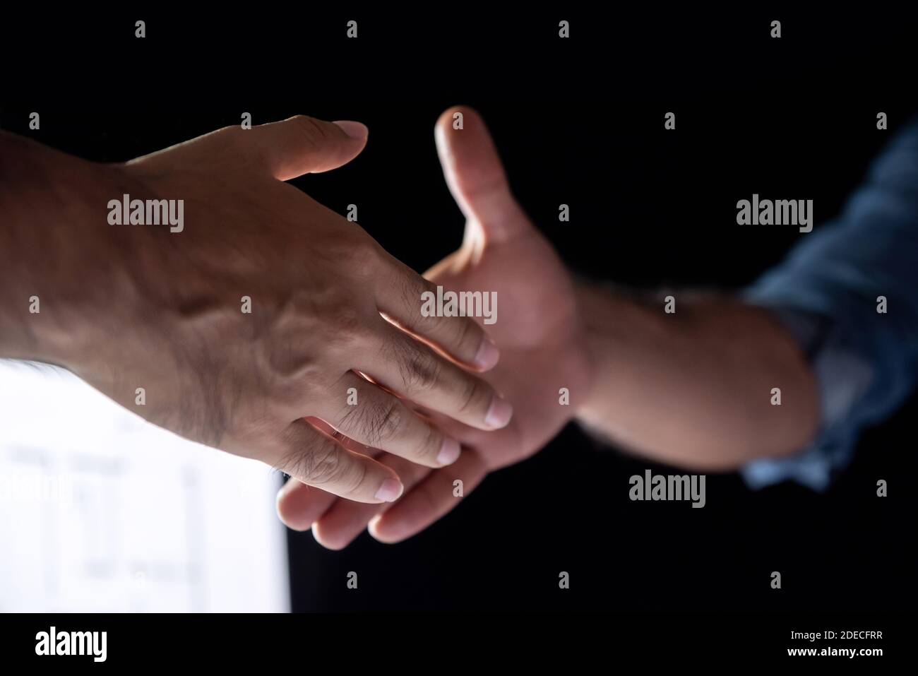 Geschäftsleute, die sich spät in der Nacht um einen Händedruck verhandelten Arbeiten im Büro Stockfoto