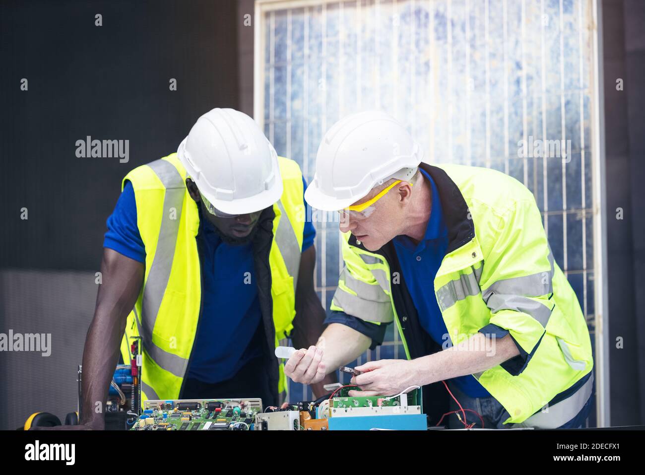 Ingenieur arbeiten Reparatur elektrische Panel mit Solarzellen Hintergrund, Konzept Teamarbeit oder Ausbildung von erneuerbaren. Stockfoto