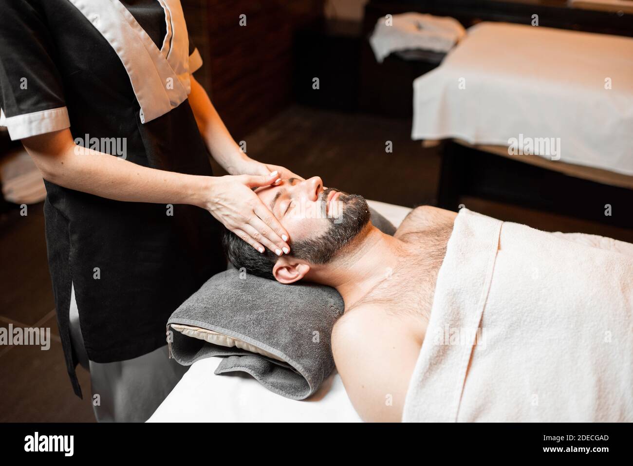 Bärtiger Mann, der eine Gesichtsmassage erhält, sich im Spa-Salon entspannt, Nahaufnahme Stockfoto