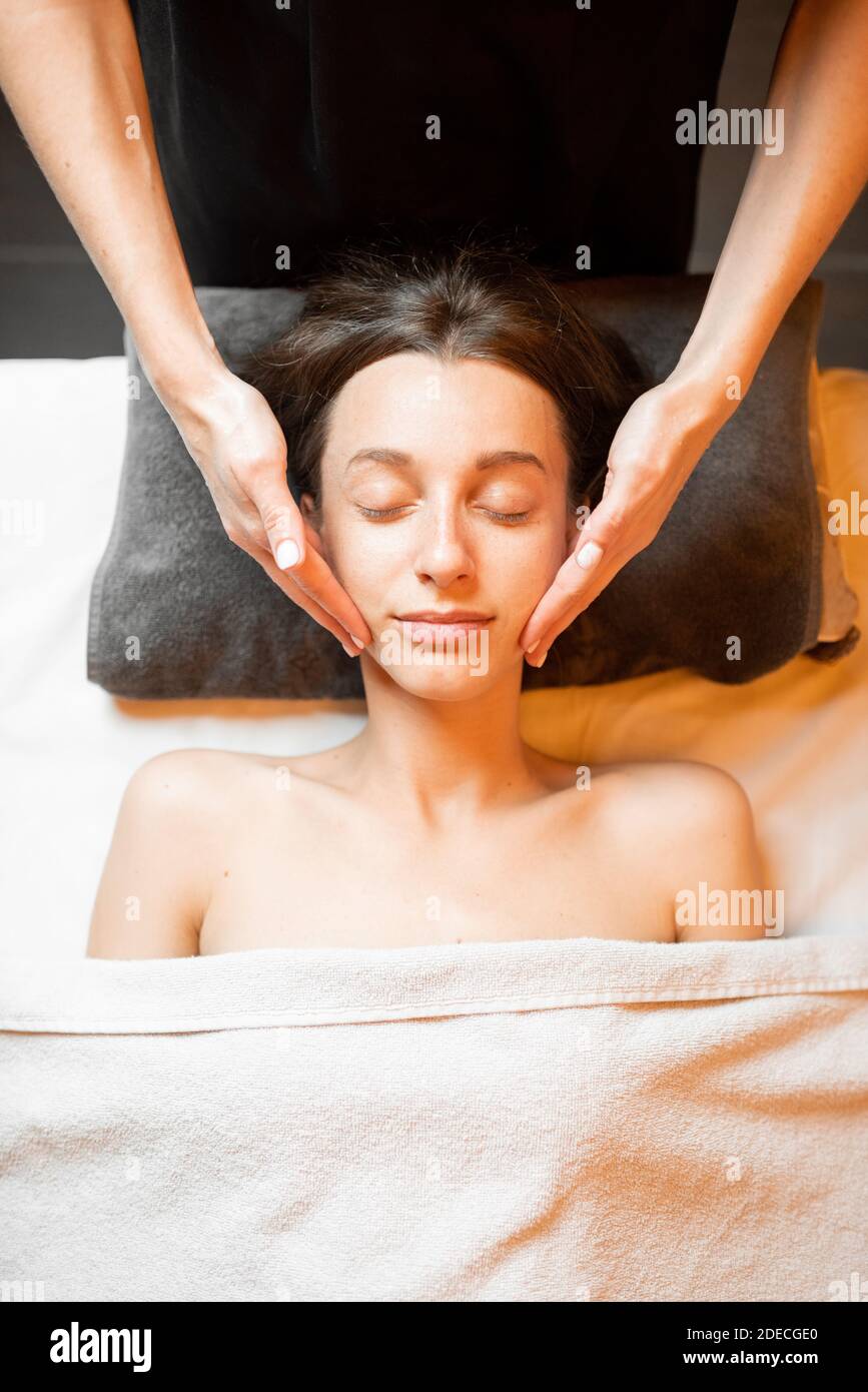 Junge Frau, die eine Gesichtsmassage erhält, sich im Spa-Salon entspannt, Blick von oben Stockfoto