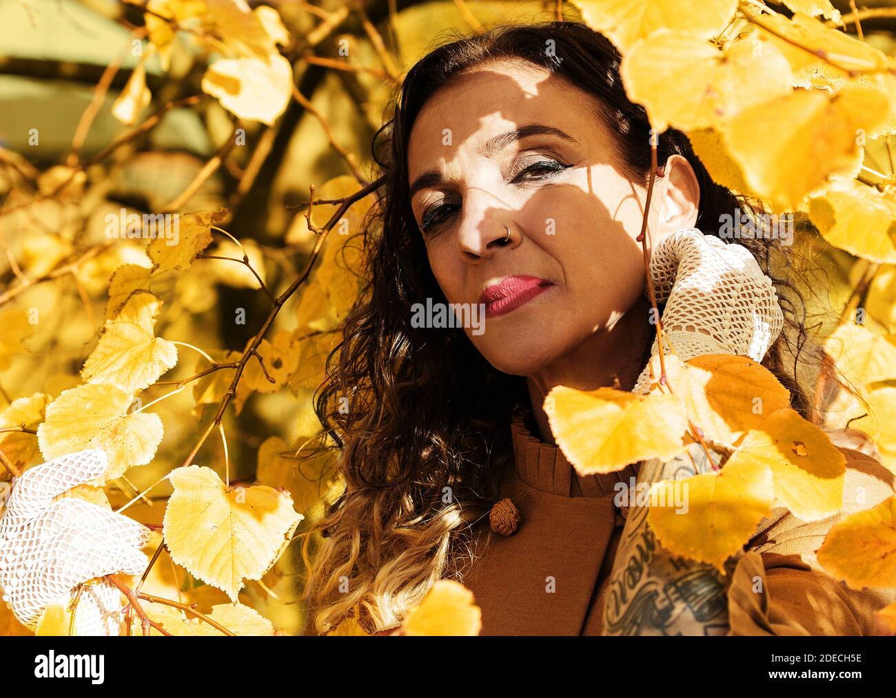 Frau unter den Zweigen eines goldenen Baumes im Herbst Stockfoto