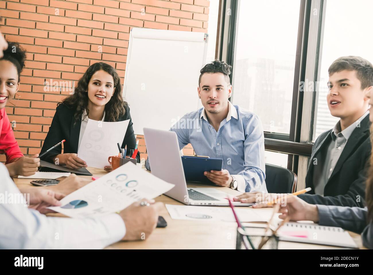 Gruppe von männlichen und weiblichen Millennial-Geschäftsmitarbeitern im Teamwork Besprechung aufmerksam zuhören, wenn Mitarbeiter eine Präsentation halten Stockfoto