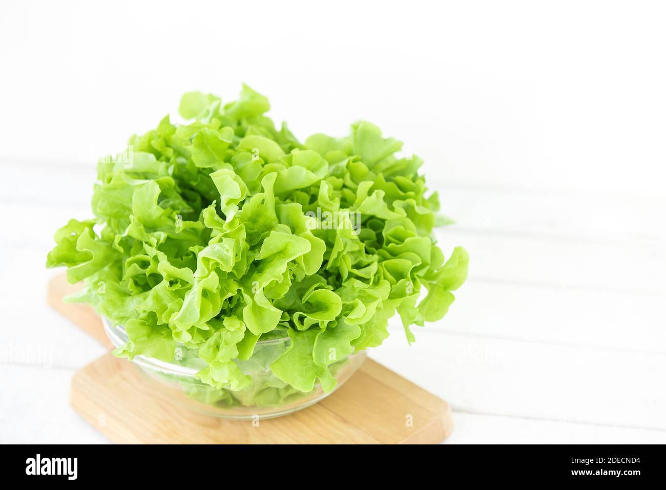 Frische Bio gesunde grüne Eiche Salat Gemüse in einer Glasschüssel auf Holzplatte in der Küche, bereit, als Salat oder kochen zu essen Stockfoto