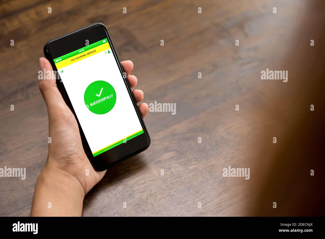 Das Smartphone mit der Hand zeigt den erfolgreichen Buchungstext auf dem Bildschirm an Abschluss der Taxireservierung online über die Anwendung Stockfoto