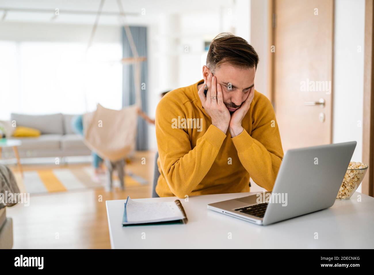Frustrierter junger Mann, der zu Hause am Laptop arbeitet Stockfoto