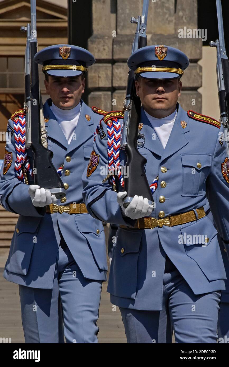 Zwei Wachposten der Prager Burgwache in ihren blassblauen Sommeruniformen marschieren mit geschulterten Gewehren mit Bajonetten, die während einer Wachwechsel-Zeremonie im ersten Burghof fixiert wurden, auf den Betrachter zu. Die Wachposten an den Toren der mittelalterlichen Burg wechseln zur vollen Stunde, und es gibt auch einen täglichen 12 Uhr mittags zeremoniellen Wachwechsel, einschließlich einer Fanfare und einer Flaggenzeremonie. Das Schloss ist der offizielle Sitz und das Büro des Präsidenten der Tschechischen Republik oder Tschechiens. Stockfoto