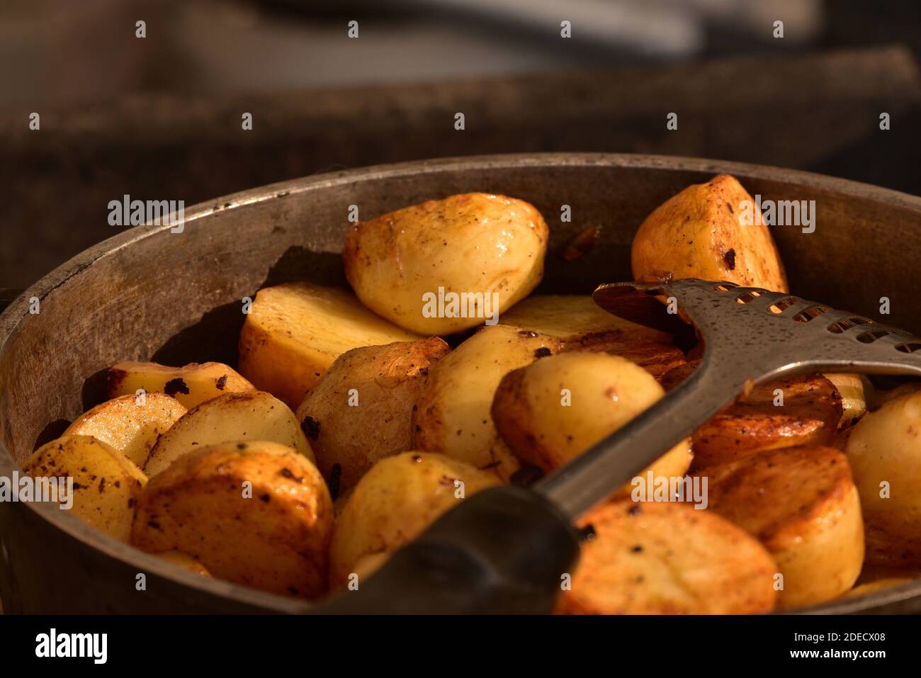 Zubereitung von gekochten Kartoffeln in einer gusseisernen Schüssel über einem offenen Feuer bei einem Picknick aus nächster Nähe. Kochen von Kartoffeln in Gusseisen über einem Feuer Stockfoto