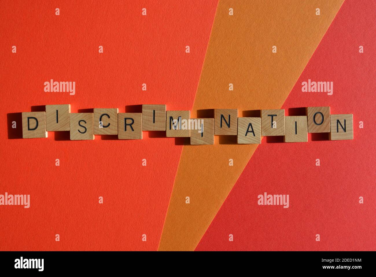 Diskriminierung, Wort in Holzbuchstaben isoliert auf rotem Hintergrund Stockfoto