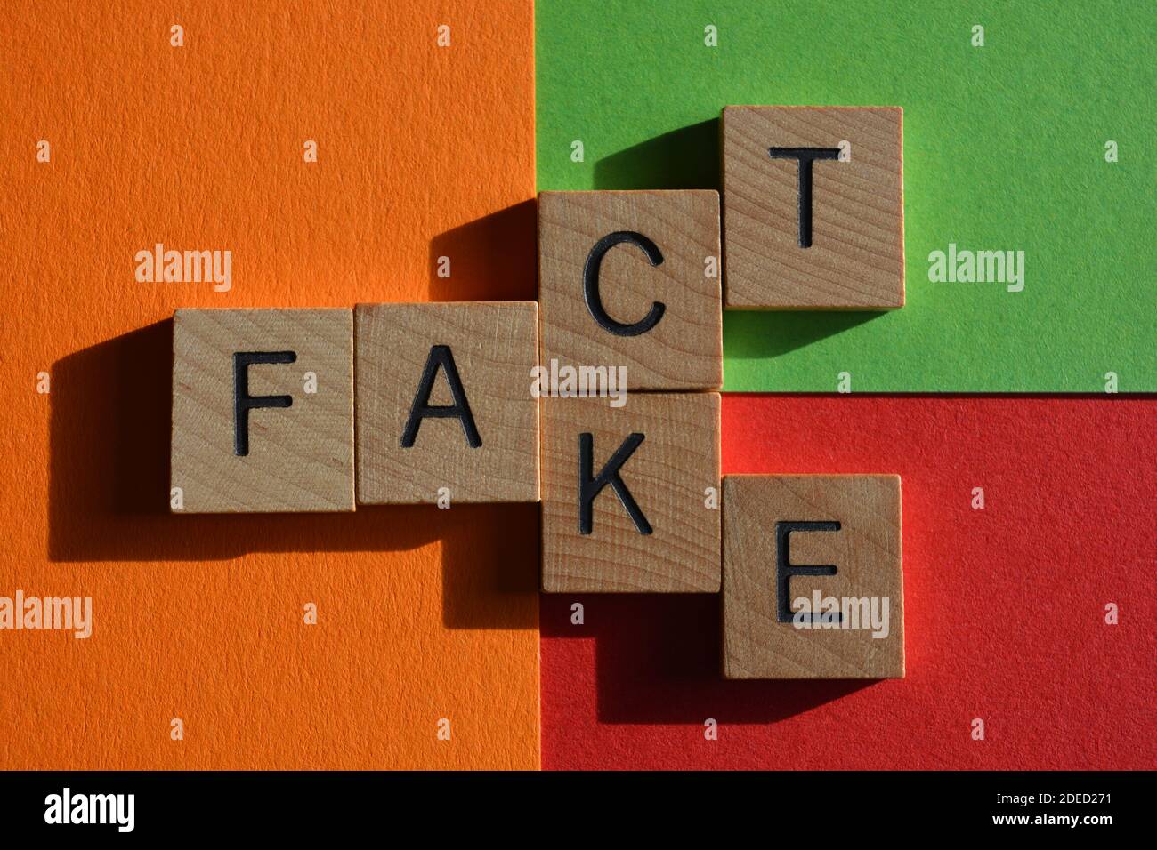 Fakt, Fälschung, Wörter in Holzalphabet Buchstaben auf rotem, orangenen und grünen Hintergrund Stockfoto