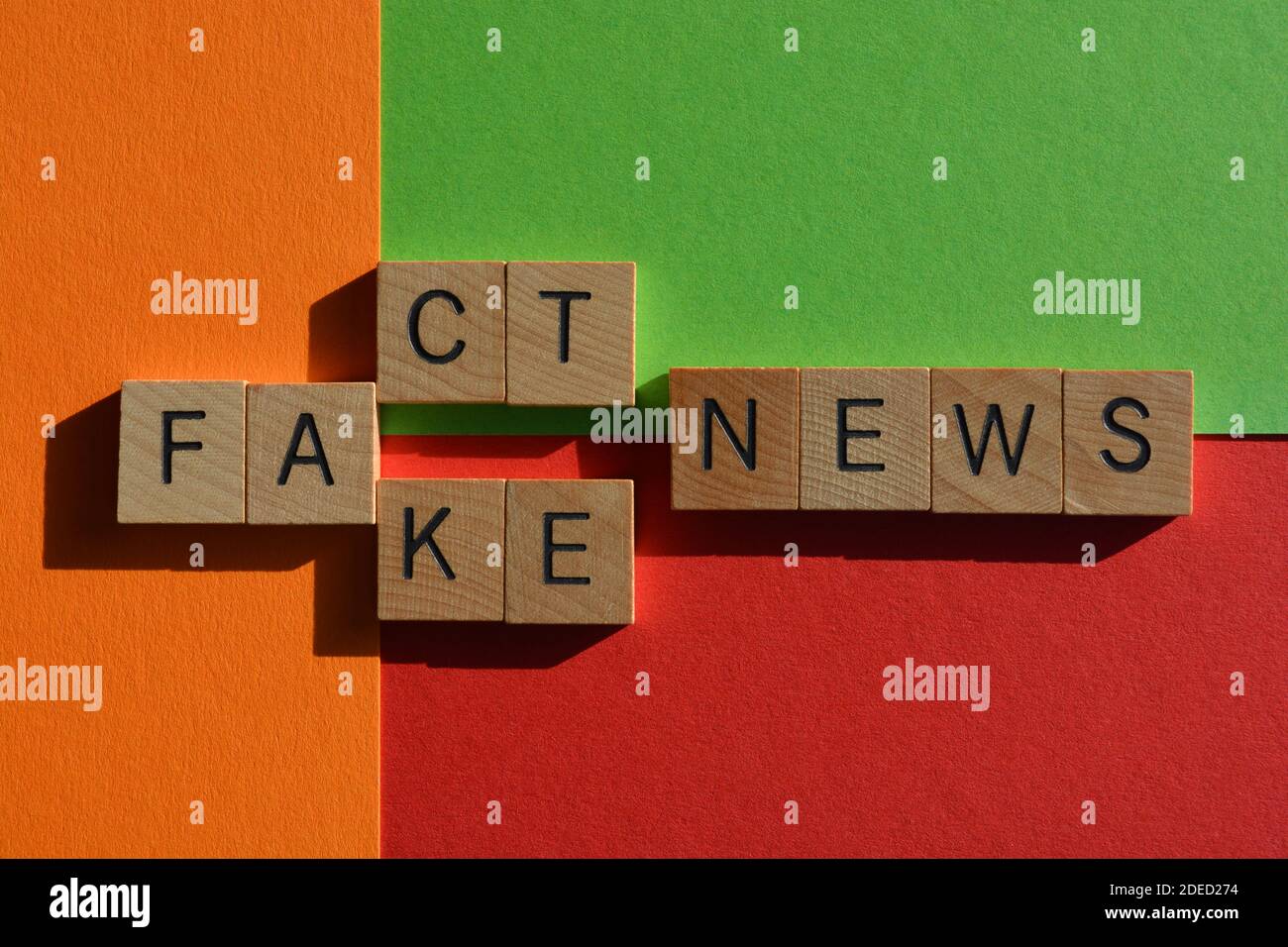 Fact, Fake, Nachrichten, Wörter in Holz-Alphabet Buchstaben auf rot, orange und grün Hintergrund. Stockfoto