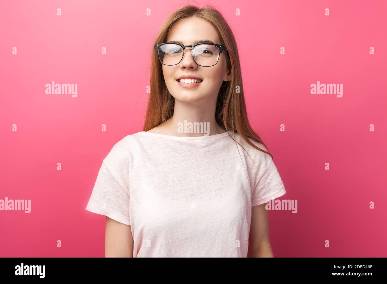 Junge attraktive Mädchen stehen in transparenten Gläsern, GA rosa Hintergrund, posiert, Stockfoto