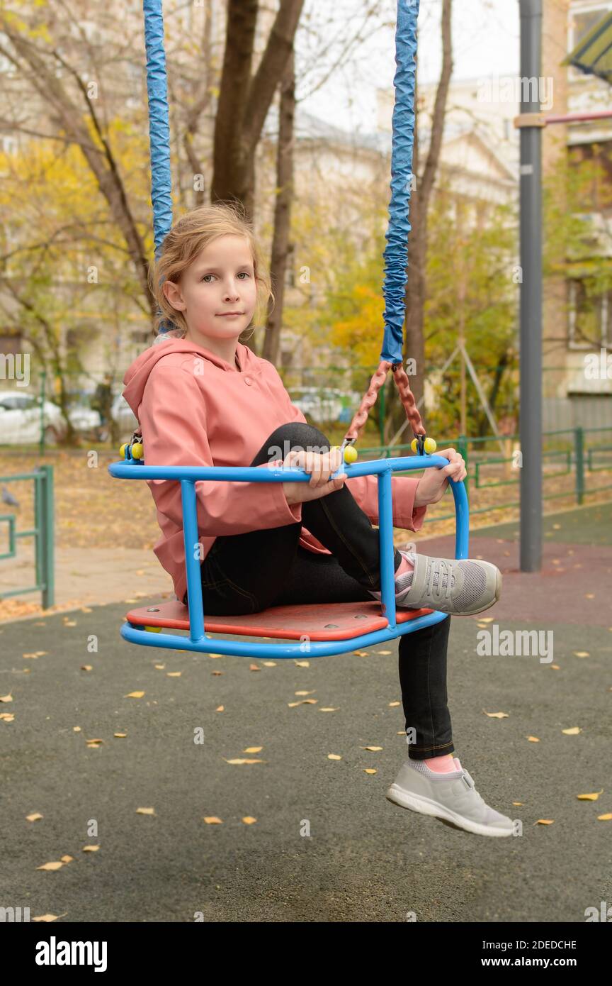 Mädchen sitzt auf einer Schaukel. Herbst Stockfoto