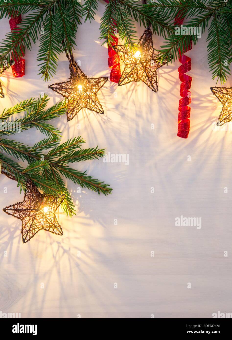 Stern Form Weihnachten Party Lichter hängen aus dem oberen Abschnitt. Grüne Fichtenzweige zur Dekoration und rot gewellte glänzende Saiten. Platz für die Chargenkopie. Stockfoto
