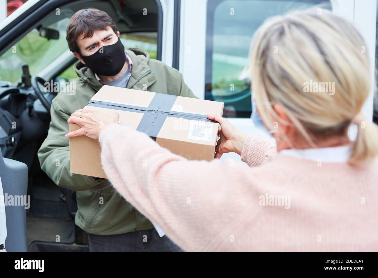 Paketzustellung Mann mit Gesichtsmaske wegen Covid-19 akzeptiert Paketzustellung für Weihnachten Stockfoto