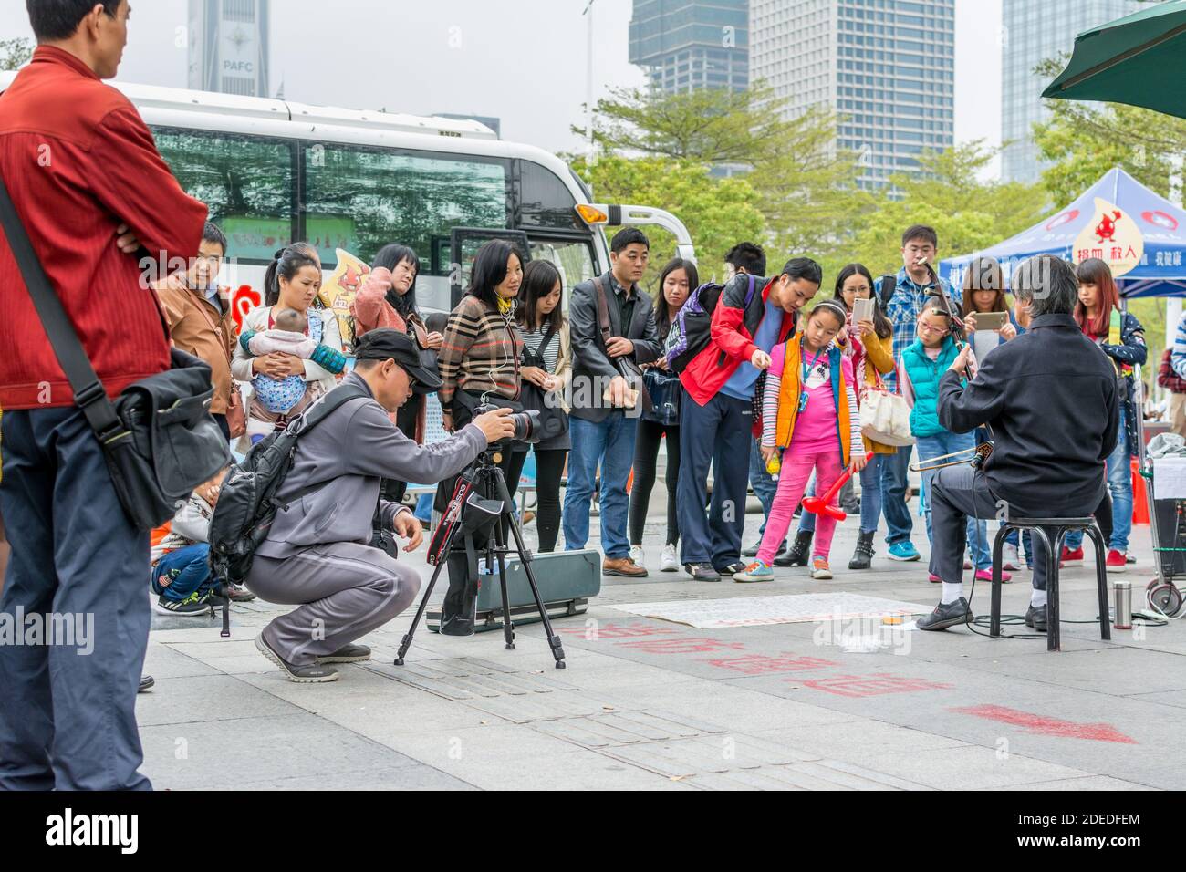 Ein Chinese, der seine Kamera beobachtete und einen Mann aufnahm, der das traditionelle chinesische Musikinstument Erhu in Shenzhen, China, spielte Stockfoto