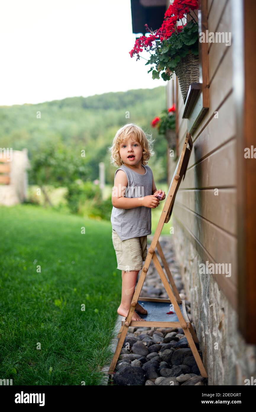 Happy kleine blonde junge spielen im Sommer im Freien von Haus. Stockfoto