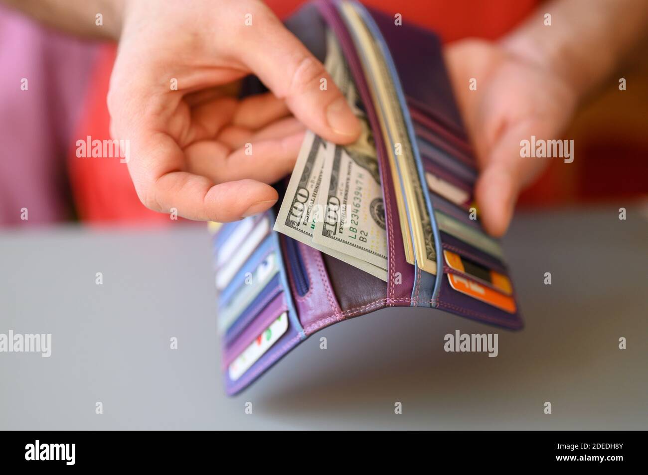 Herren Hände halten 100 Dollar Scheine und eine Brieftasche auf Ein grauer Tisch Stockfoto