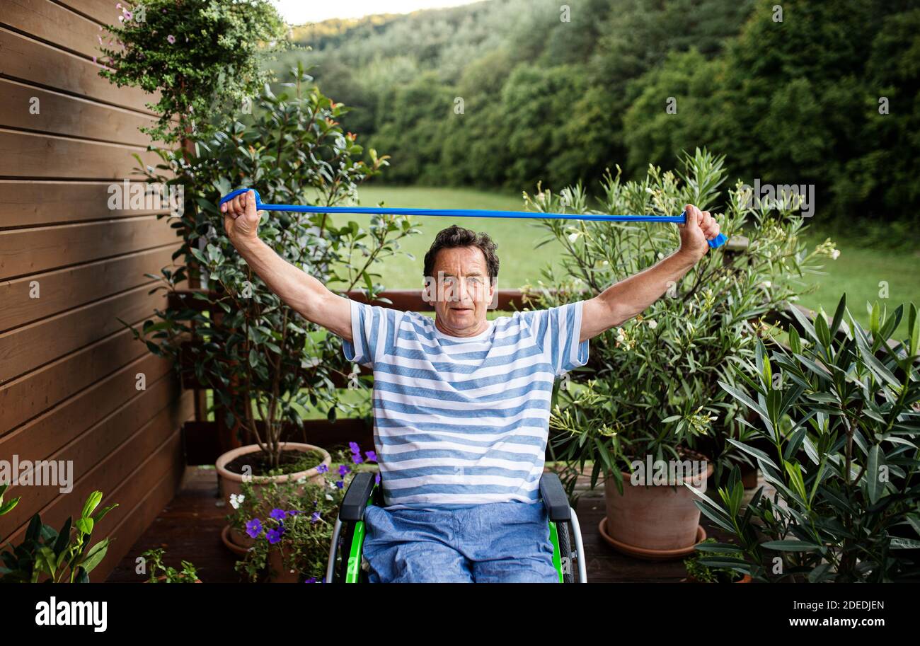 Älterer Mann im Rollstuhl, der auf der Terrasse trainieren kann. Stockfoto
