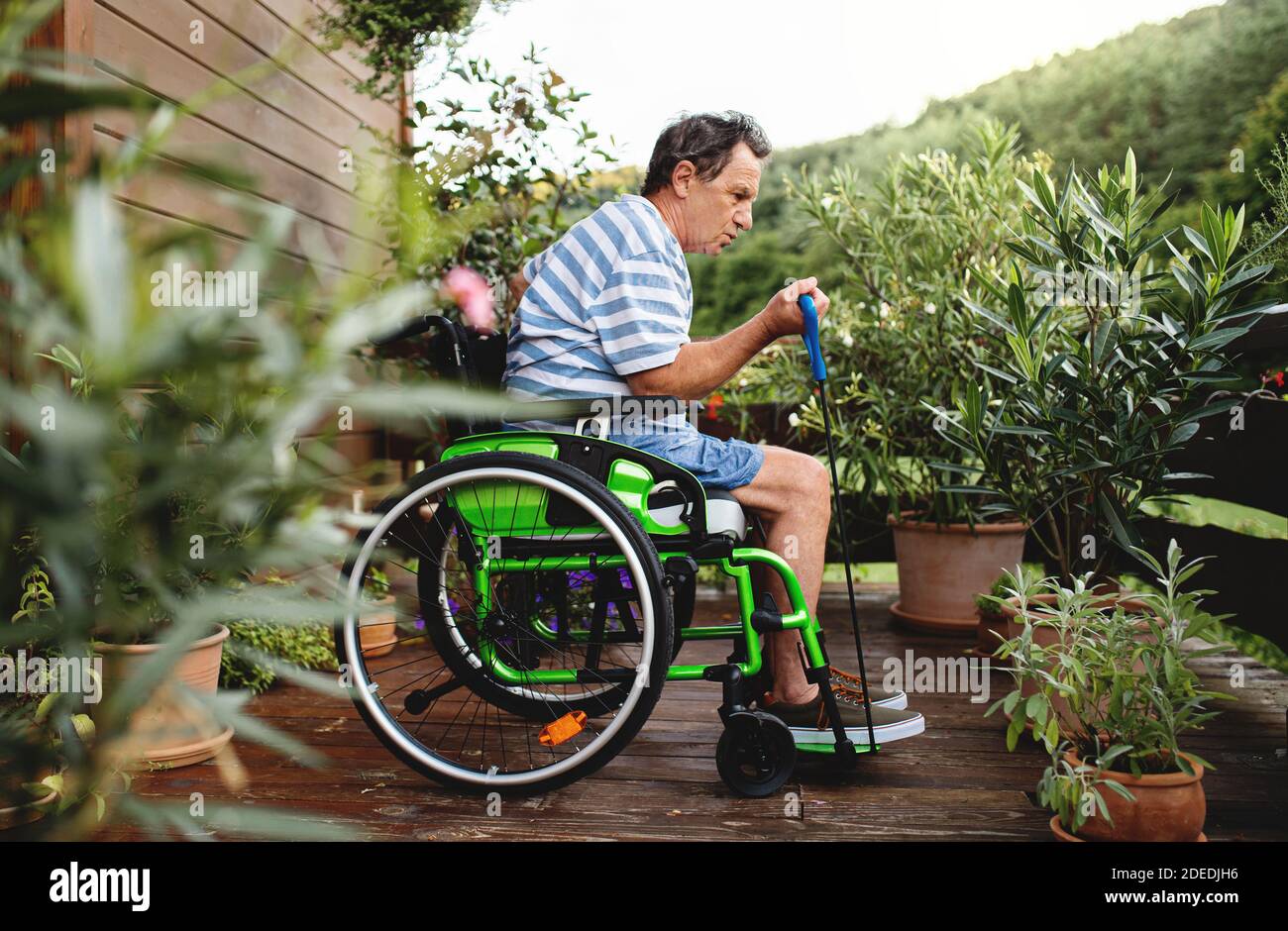 Älterer Mann im Rollstuhl, der auf der Terrasse trainieren kann. Stockfoto