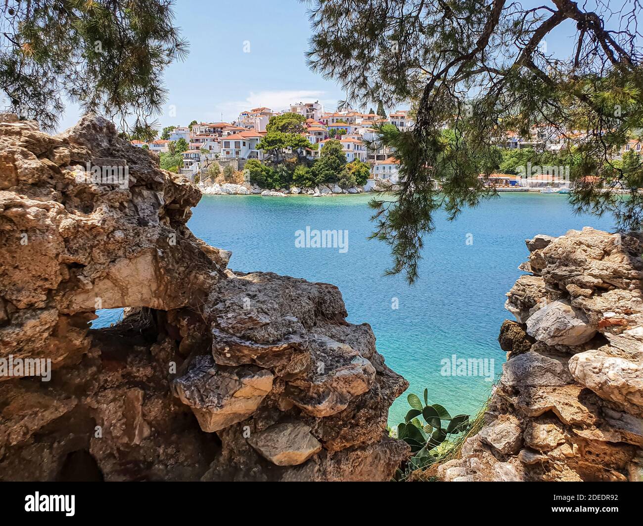 Blick durch Steine auf die Altstadt von Skiathos auf der Insel Skiathos, Griechenland. Stockfoto