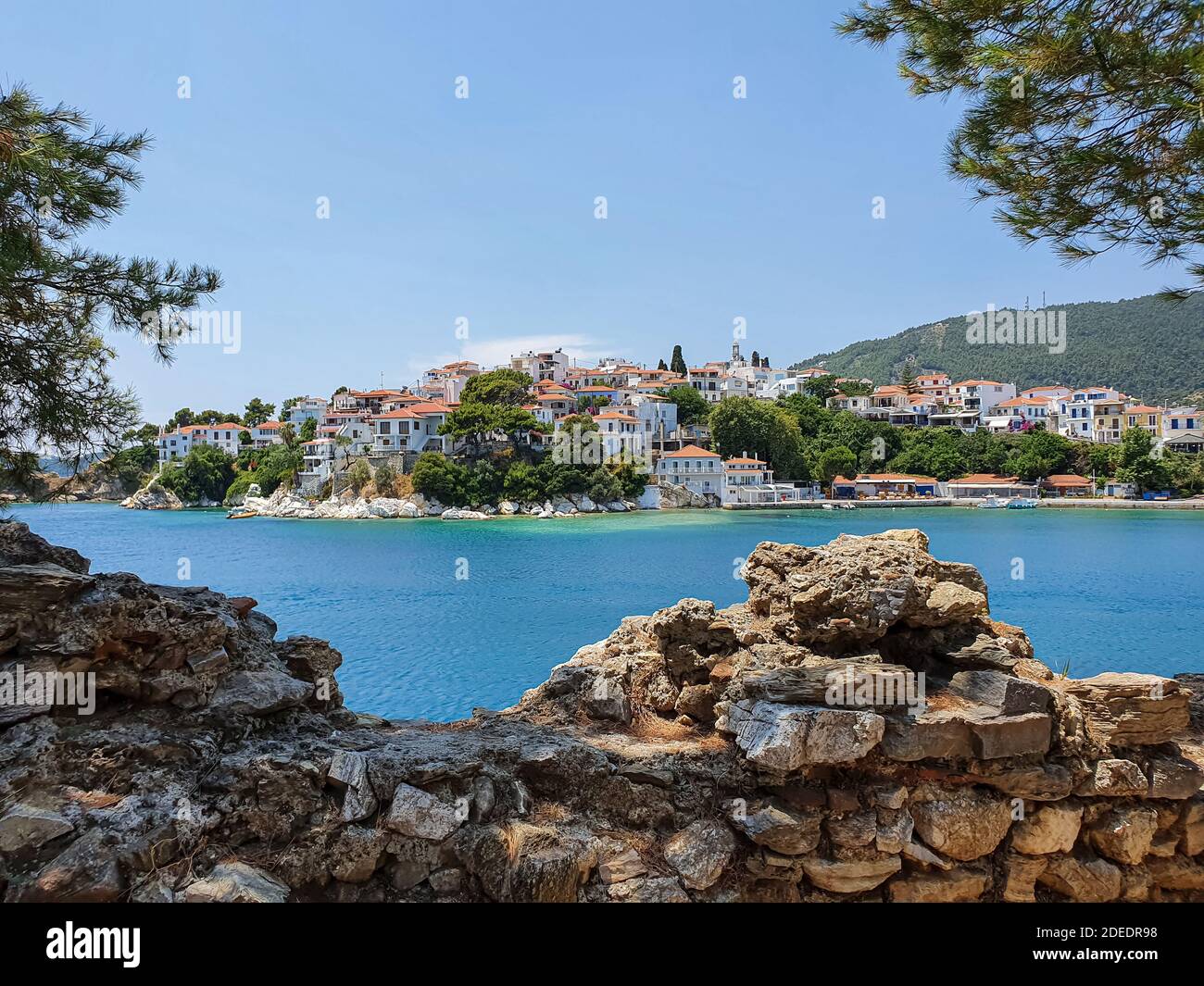 Blick durch Steine auf die Altstadt von Skiathos auf der Insel Skiathos, Griechenland. Stockfoto