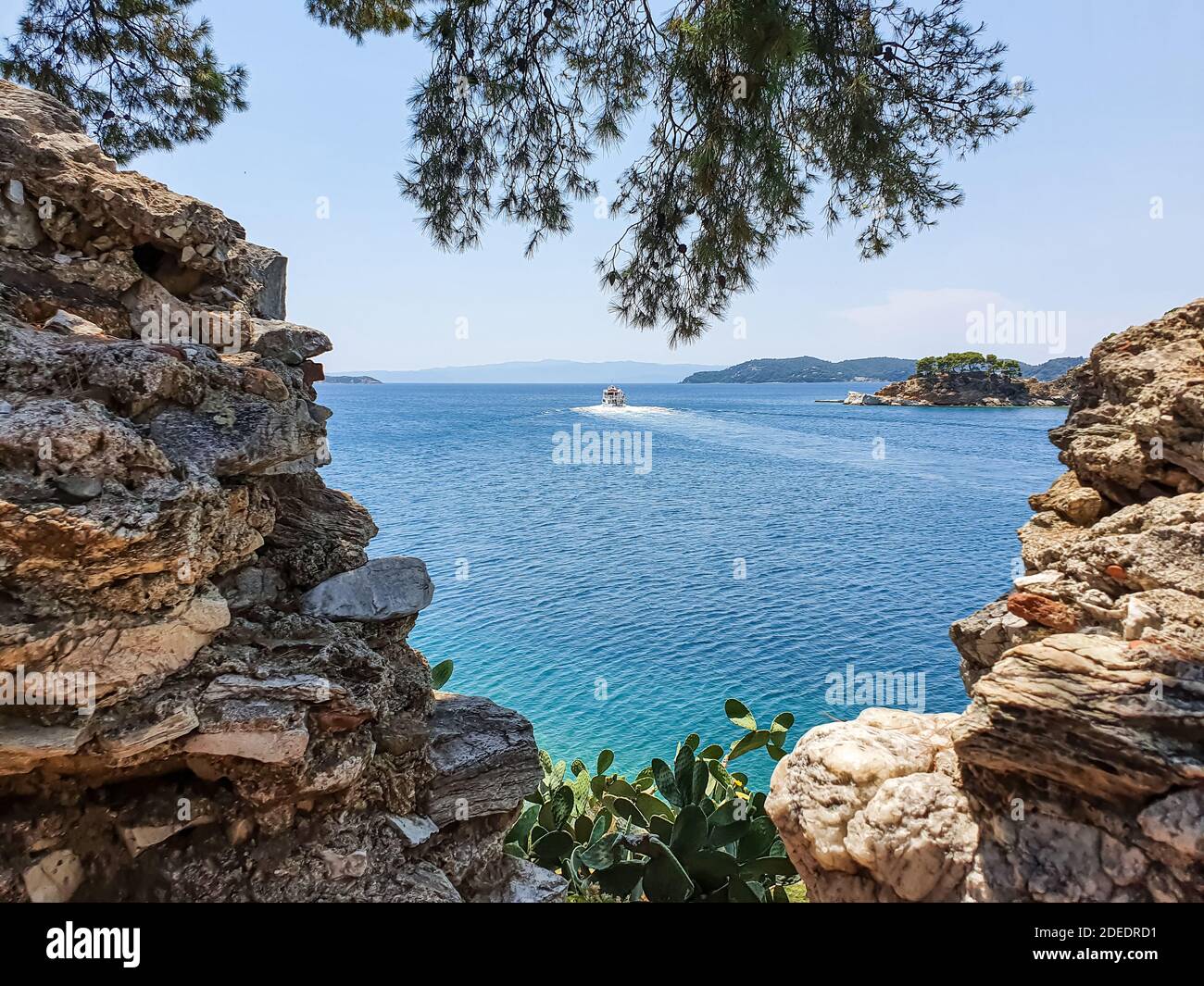 Blick durch Steine auf die Altstadt von Skiathos auf der Insel Skiathos, Griechenland. Stockfoto