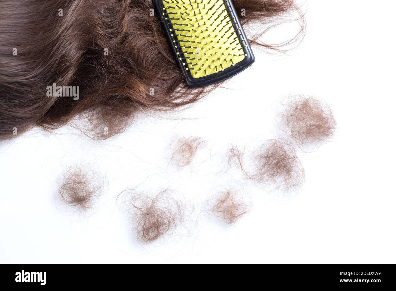 Haarbürste auf dem Haar und die Klumpen des losen Haares auf dem weißen Hintergrund. Stockfoto