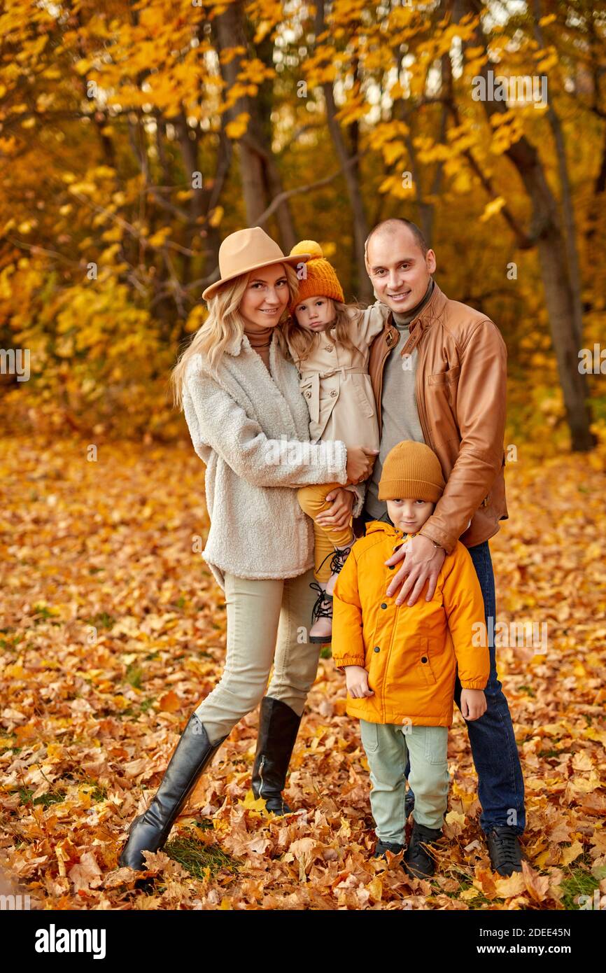 Ganzkörperportrait von lieblichen Familie mit Kindern im Herbst sonnigen Wald, kaukasischen Eltern und Kinder in Mänteln posiert vor der Kamera Stockfoto Ganzkörperportrait von lieblichen Familie mit Kindern im Herbst sonnigen Wald, kaukasischen Eltern und Kinder in Mänteln posiert vor der Kamera Stockfoto