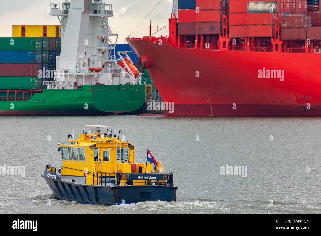 Gelbes holländisches Lotsenboot im Hafen von Rotterdam mit Container Frachtschiffe im Hintergrund Stockfoto