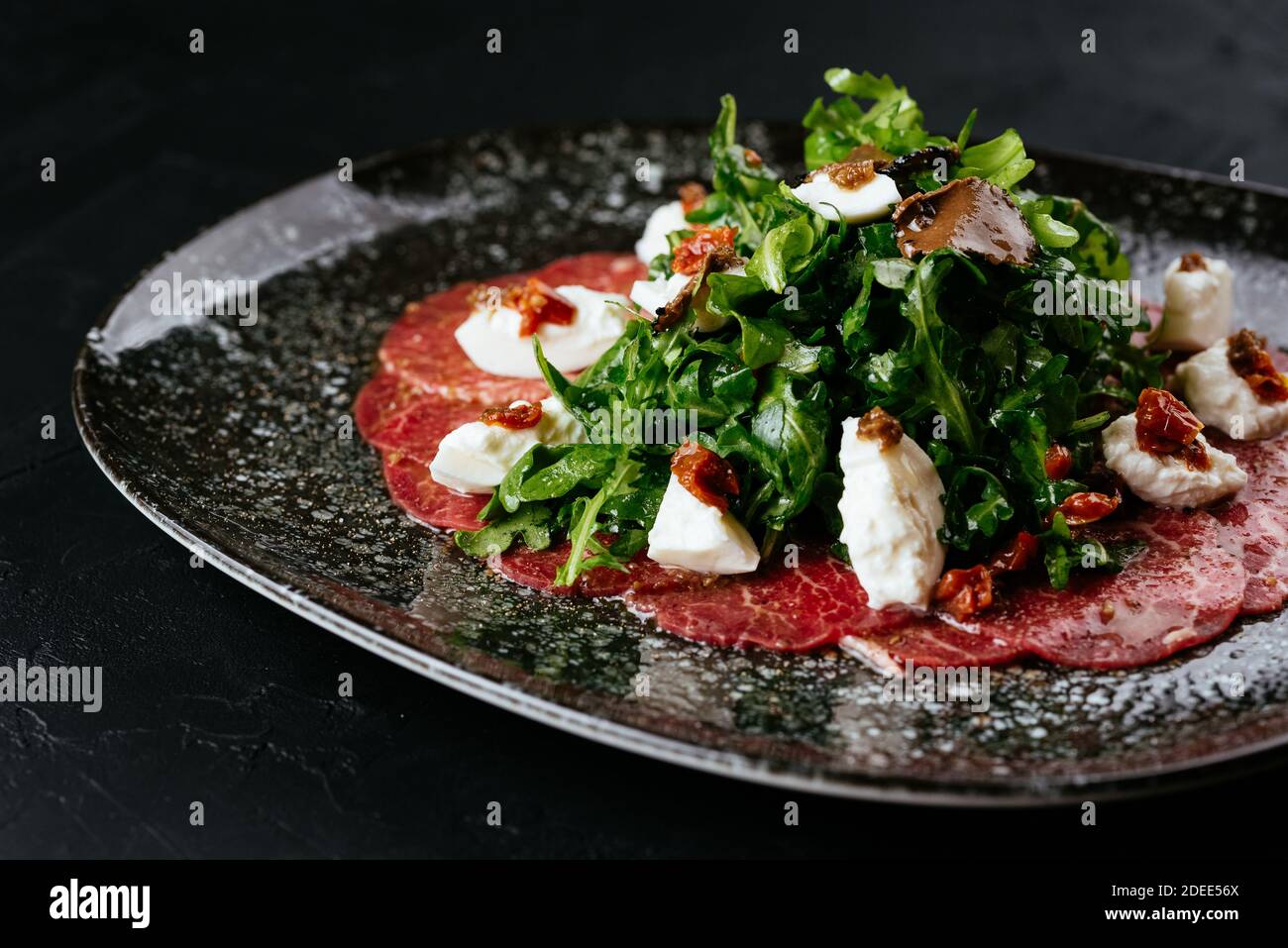 Carpaccio aus Rindfleisch aus Marmor auf schwarzem Hintergrund Stockfoto