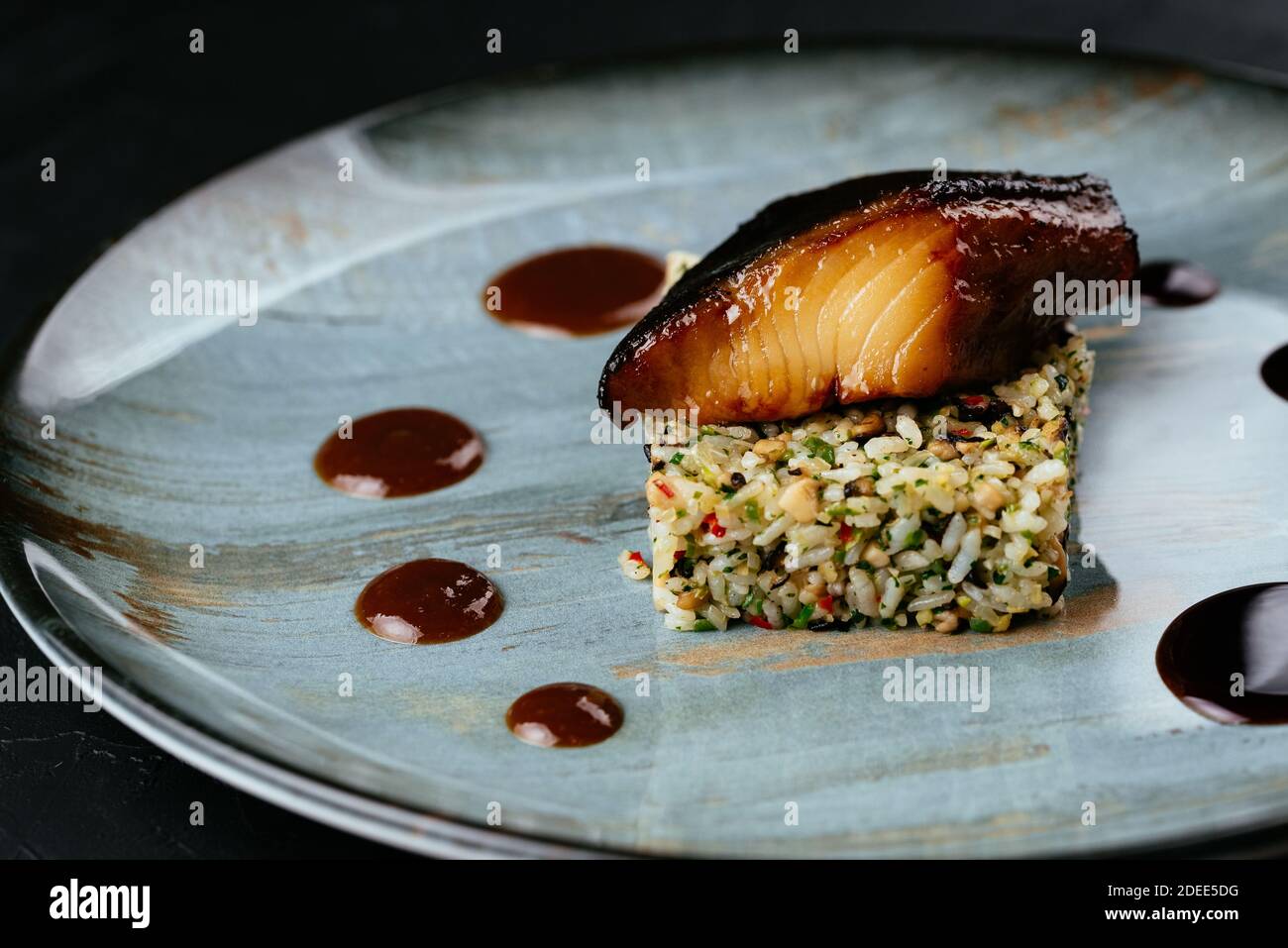 Gegrillter Fisch mit Reis und Gemüse auf schwarzem Hintergrund Stockfoto
