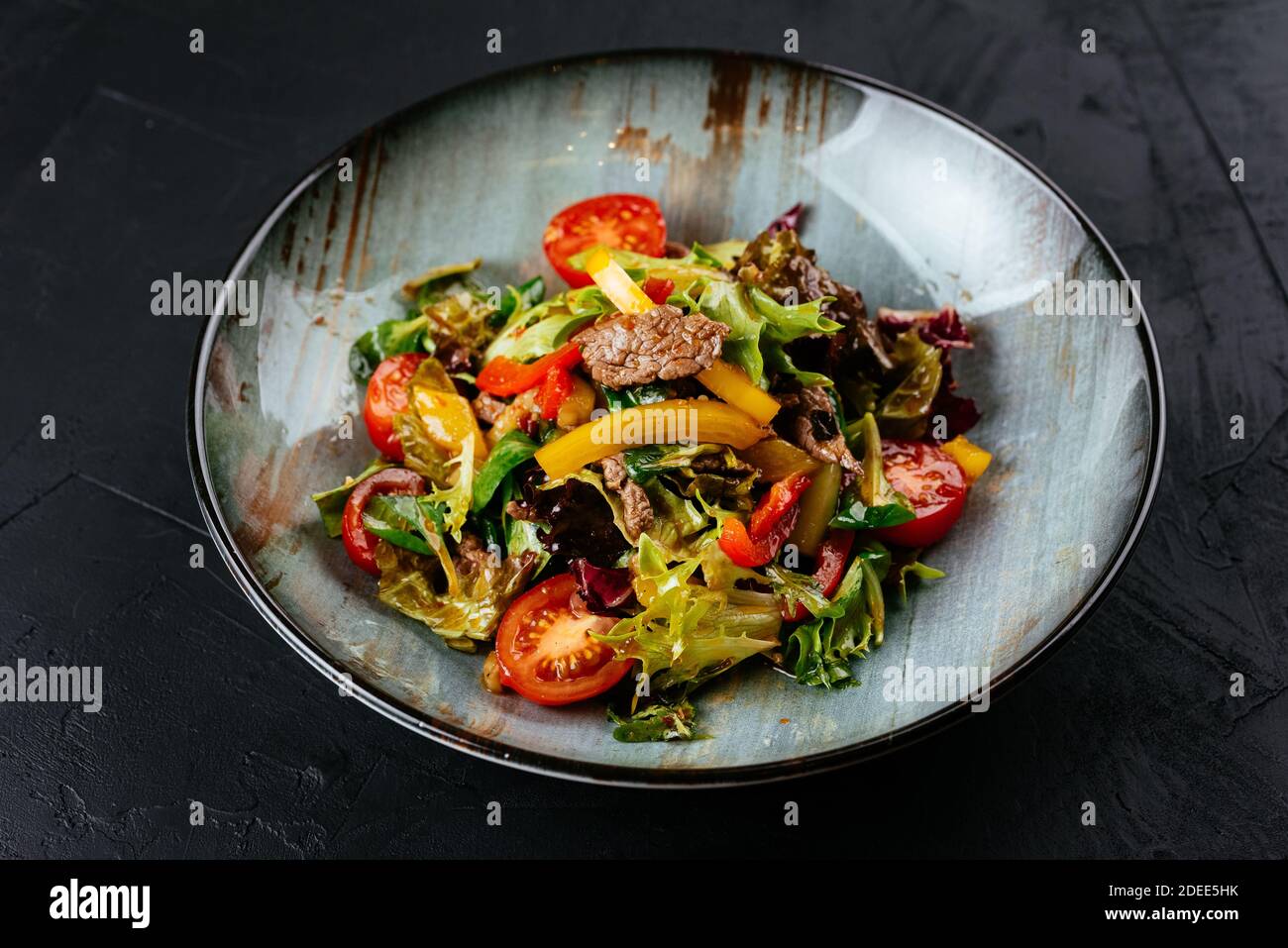 Warmer Salat mit marmorierten Rindersteaks auf schwarzem Hintergrund Stockfoto