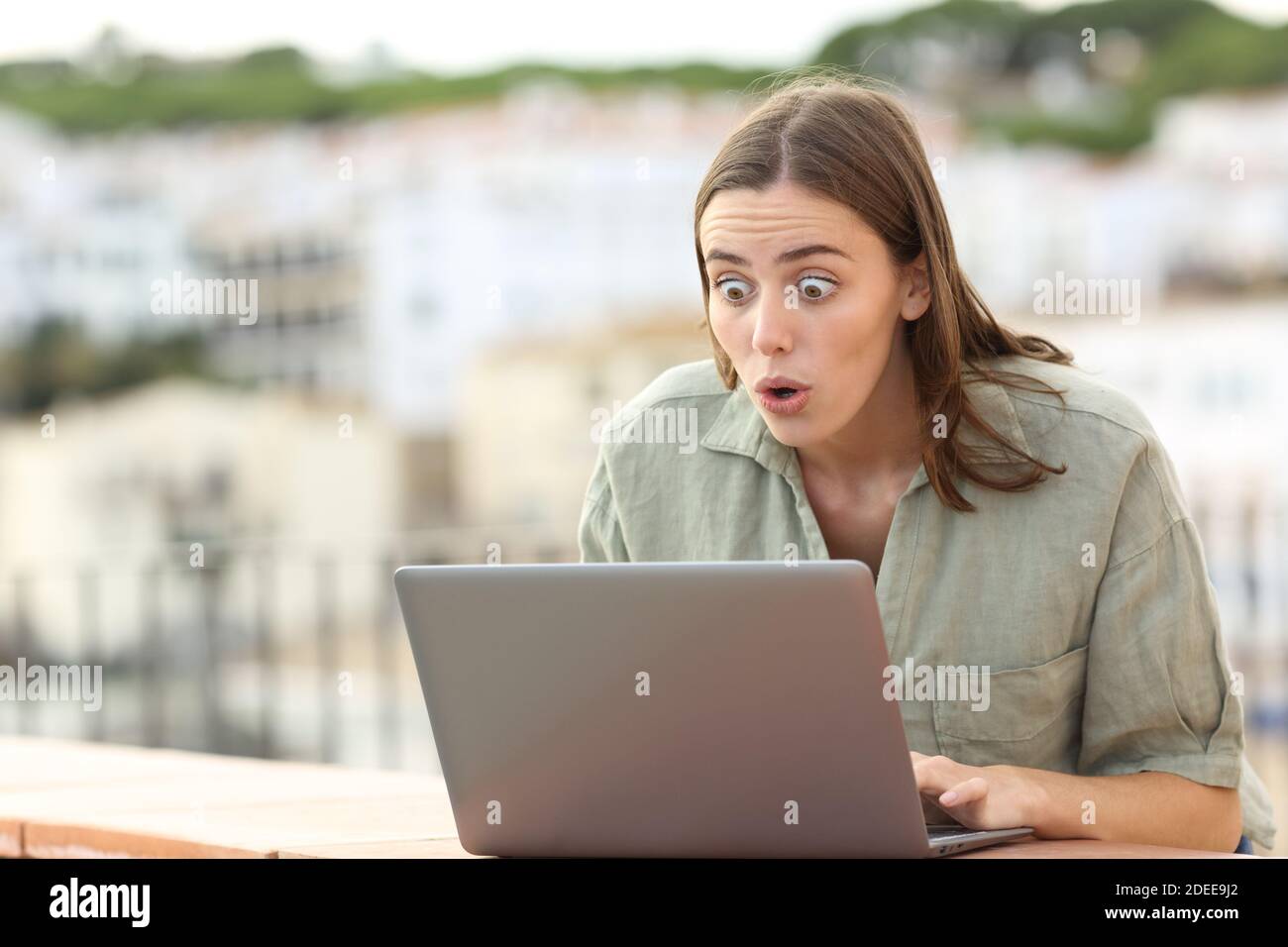 Ich war überrascht, dass ein Tourist auf dem Balkon des Apartments den Inhalt eines Laptops in einem überprüfte Stadt Stockfoto