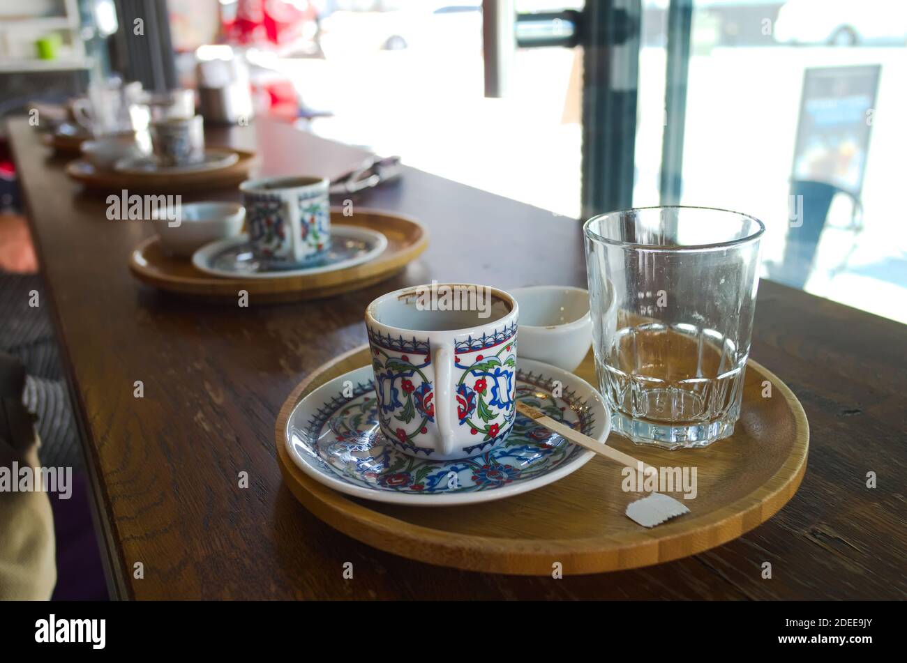 Leere Tasse türkischen Kaffee mit traditionellem Patter im Café und leeres Glas Wasser aus der Nähe. Selektiver Fokus auf die erste Tasse. Istanbul, Türkei. Stockfoto