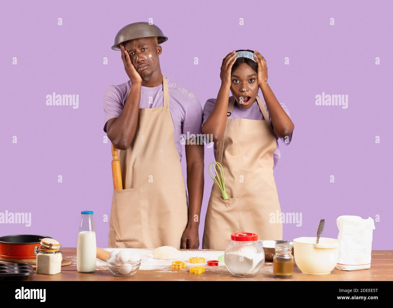 Backkatastrophe Konzept. Verzweifelte junge schwarze Paar Schwierigkeiten beim Kochen über lila Hintergrund Stockfoto
