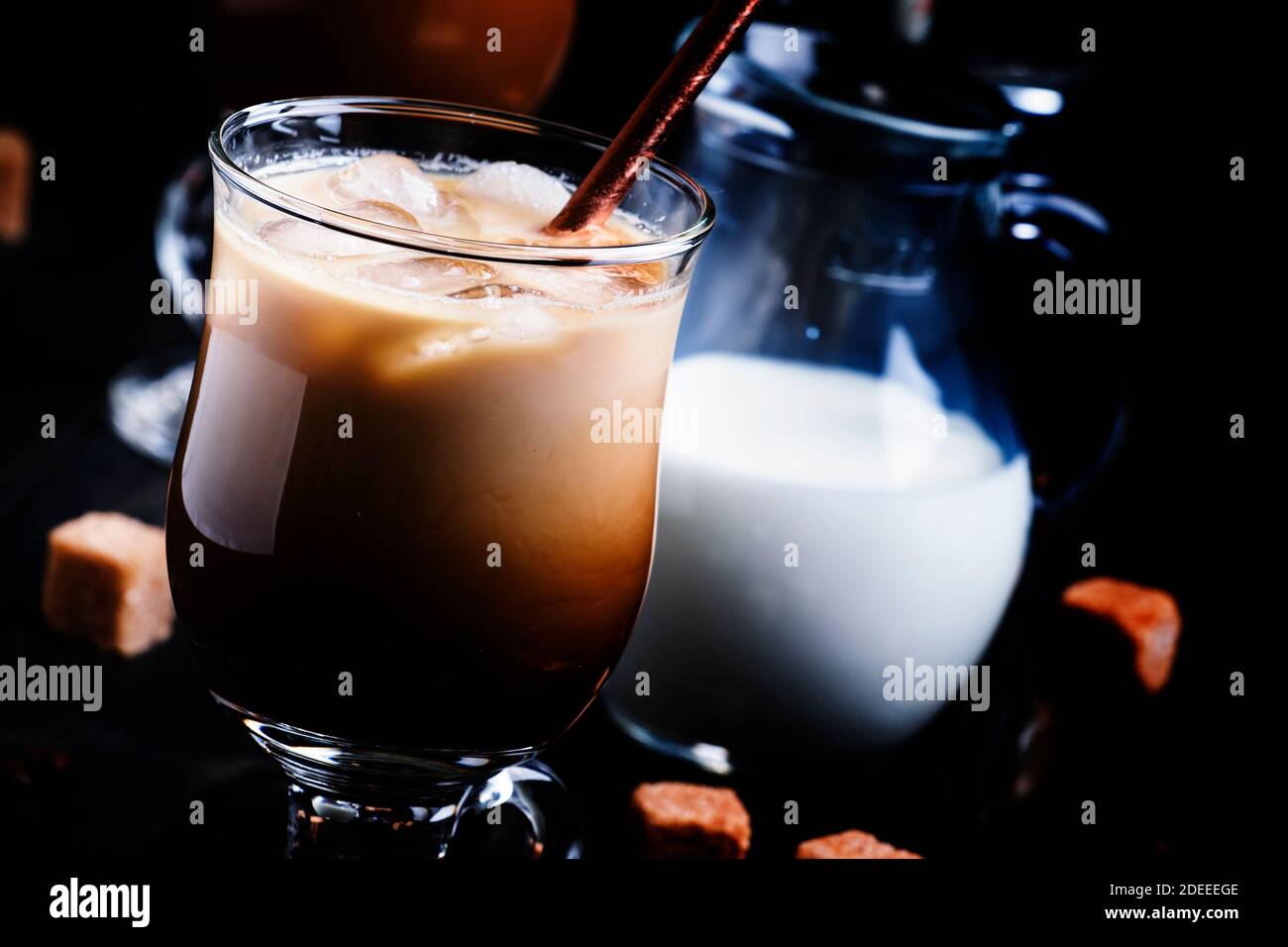 Eiskaffee im Glas, Milch, Zucker und Kaffeemaschine, dunkler Hintergrund, selektiver Fokus Stockfoto