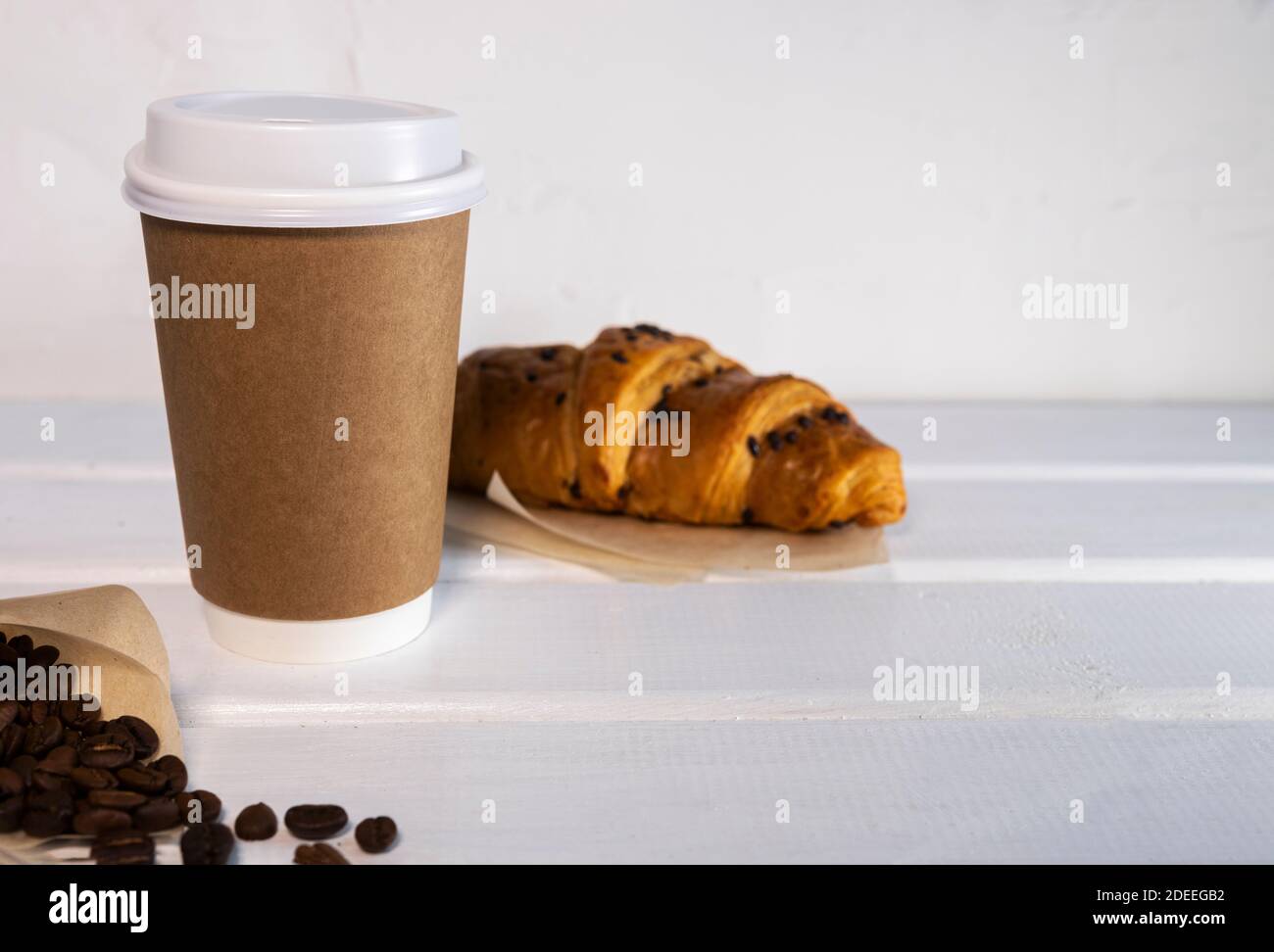 Take Away Kaffee in Papier Eco Cup und frische Croissant mit Schokolade Tropfen auf Holz Hintergrund, Copy Space Stockfoto