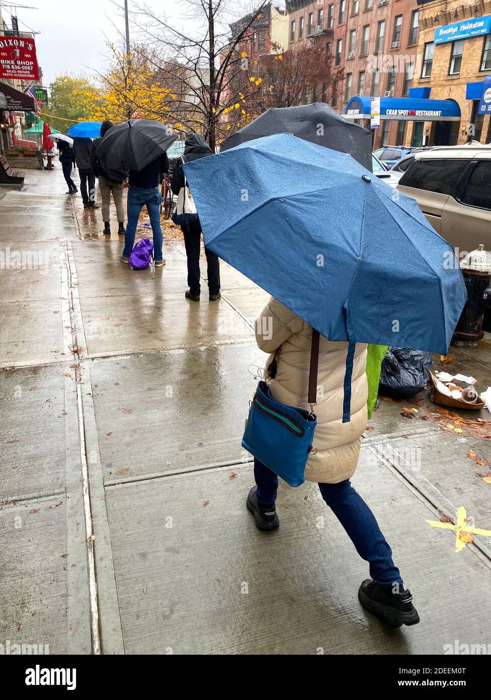 An einem regnerischen Herbsttag während der Covid-19-Pandemie stehen die Leute Schlange, um im Park Slope Food Coop einzukaufen. Stockfoto