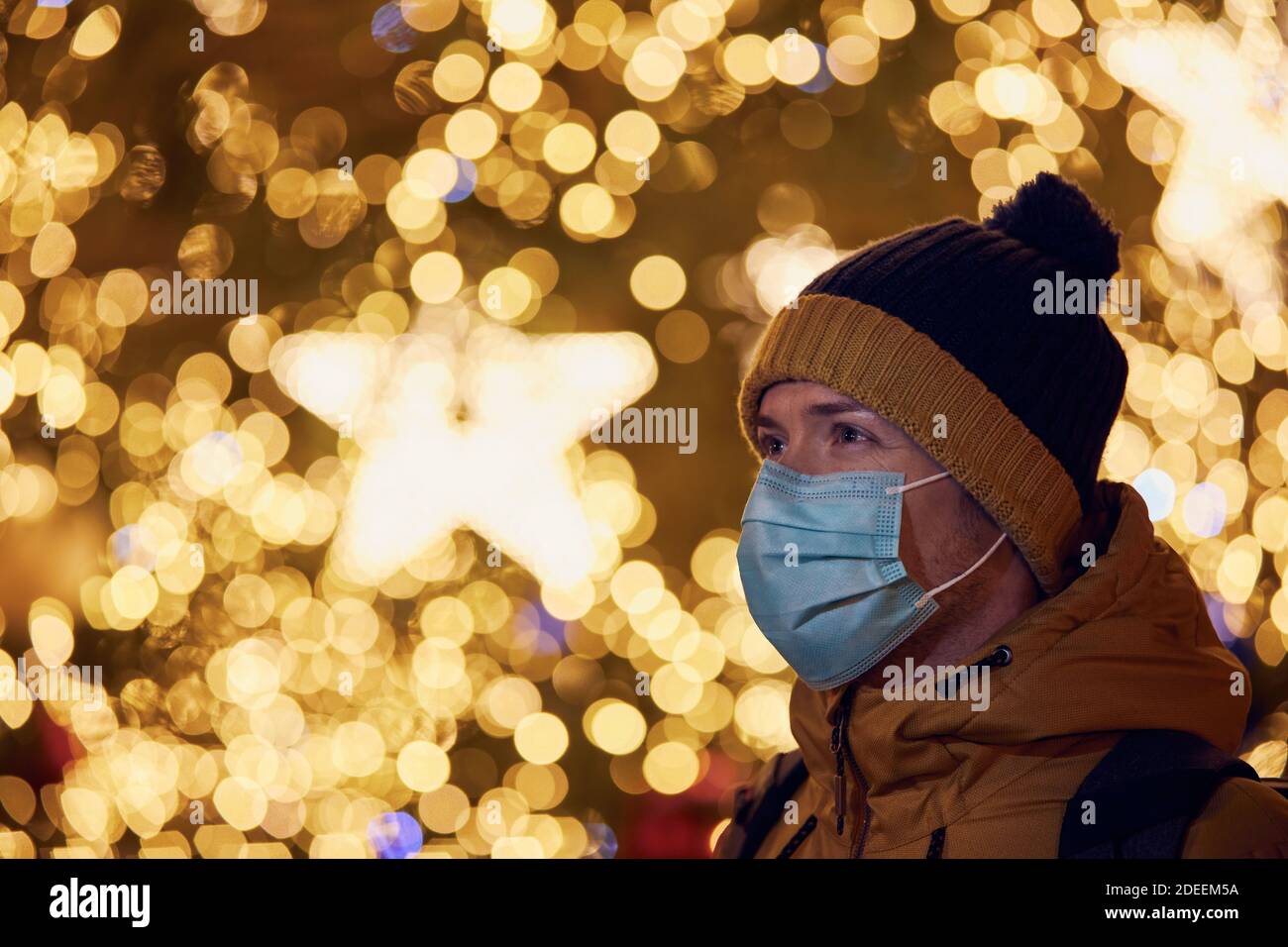 Junger Mann mit Gesichtsmaske gegen Weihnachtsbaum in Prag. Themen Coronavirus-Pandemie während der Weihnachtsfeiertage und persönliche Verantwortung. Stockfoto