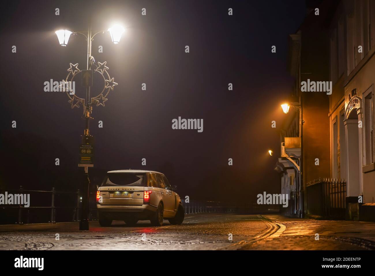Der Range Rover parkte nachts in einer Straße mit Häusern in Großbritannien zur Weihnachtszeit unter einer Straßenlaterne. Stockfoto