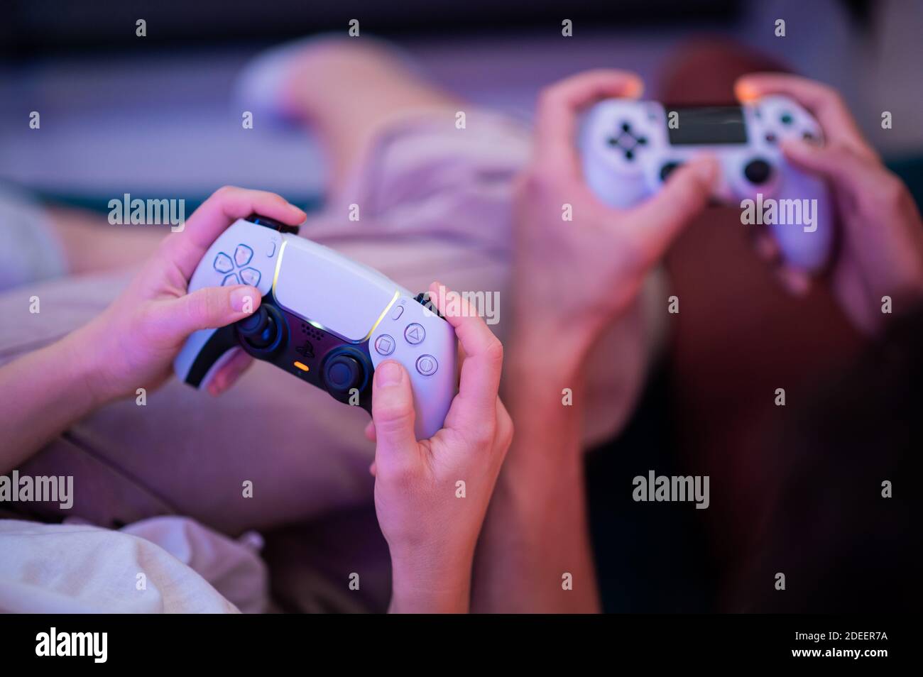 Verschiedene Generationen von PlayStation-Konsolen-Controllern: PS5 DualSense-Controller und PS4 DualShock-Controller in den Händen von Spielern. Moskau - Stockfoto