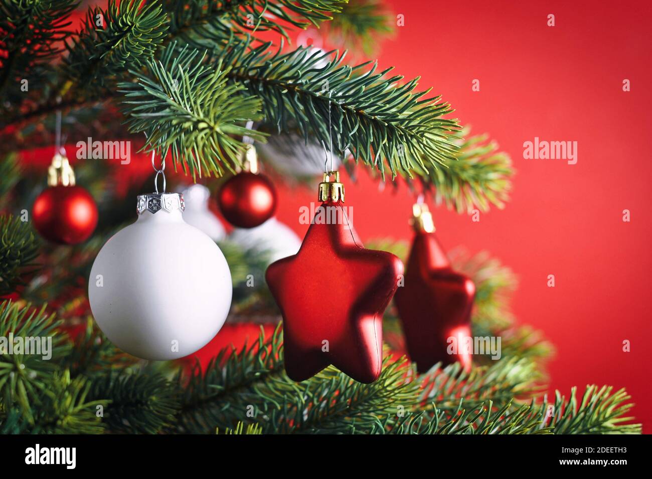 Nahaufnahme von dekorierten Weihnachtsbaum mit roten Stern geformt Und weiße Kugel formt Baum Ornament Kugeln auf rotem Hintergrund Stockfoto