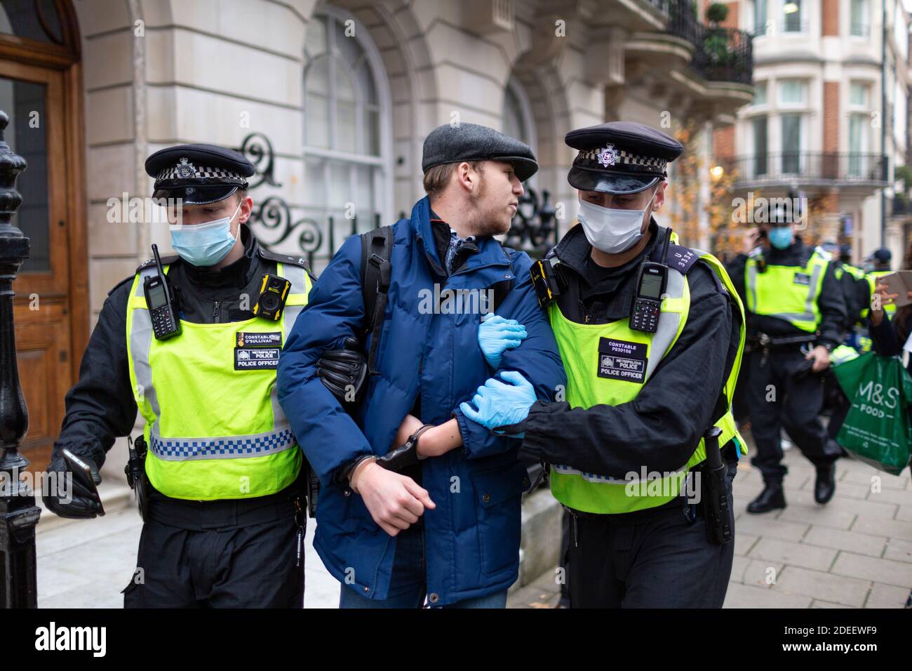 Anti-Lockdown Protest, London, 28. November 2020. Ein festgestellter Protestler blickt zurück, als er von Polizisten weggeführt wird. Stockfoto